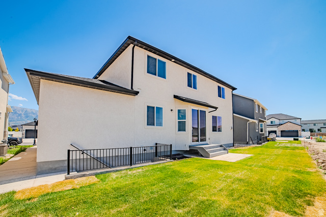 45 North Scarlet Maple Road, Unit 4317 Vineyard, UT 84059 - Photo 3 of 35 Rear exterior featuring a stucco finish, multi-pane windows, a black roofline, and sliding glass doors leading to a concrete patio and a grassy yard