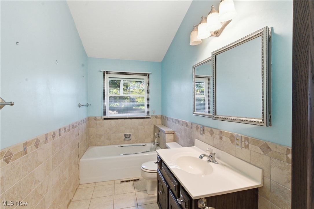 54846 Seneca Lake Road Quaker City, OH 43773 - Photo 21 of 42 Full bath featuring tile walls, a wainscoted wall, a bath, vanity, and light tile patterned floors