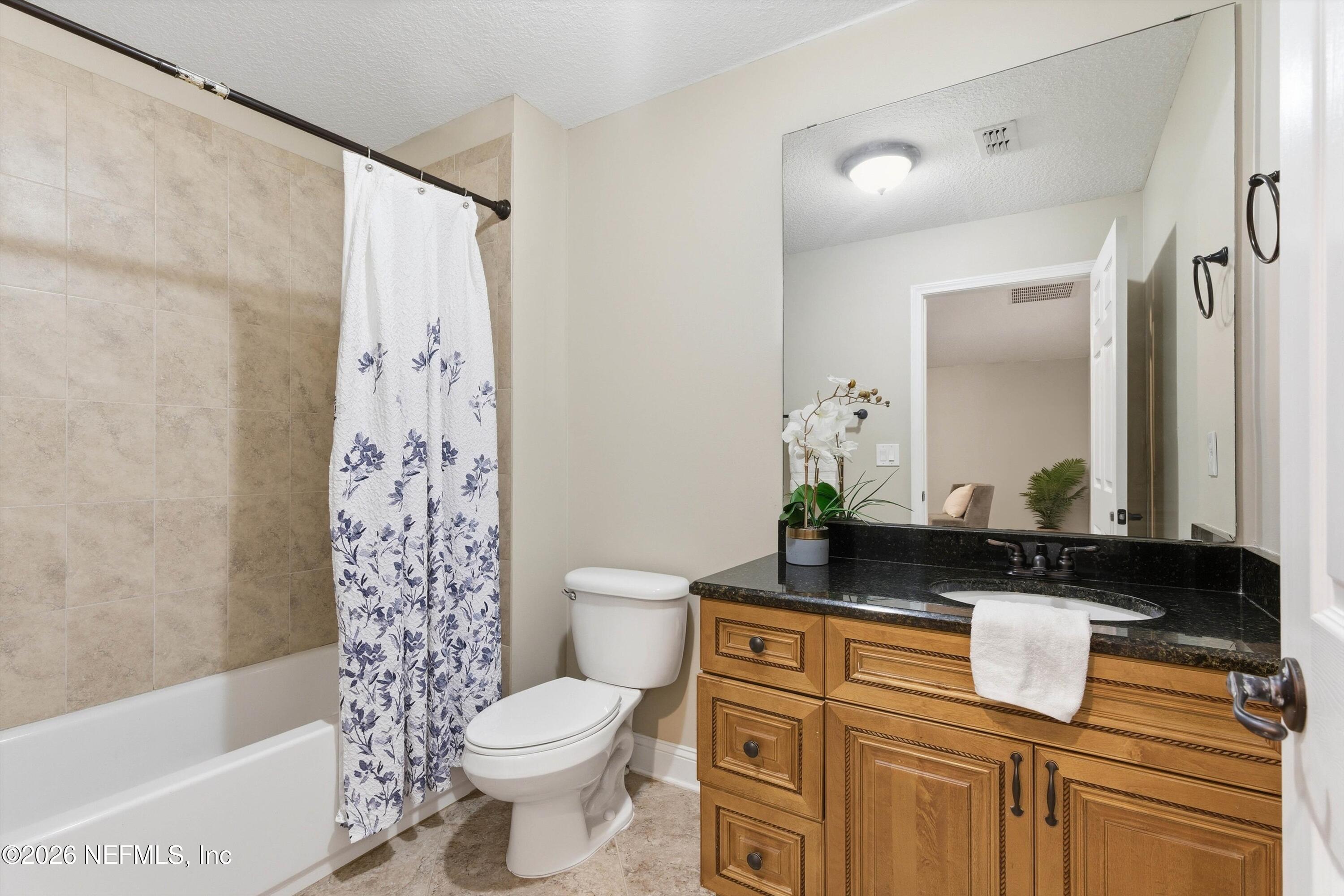 1733 Sanctuary Way Fleming Island, FL 32003 - Photo 30 of 39 a bathroom with a granite countertop sink a toilet a mirror and shower