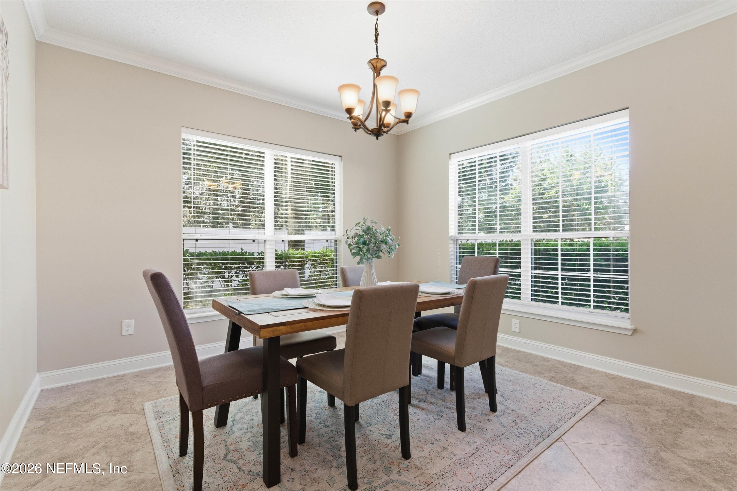 1733 Sanctuary Way Fleming Island, FL 32003 - Photo 4 of 39 a dining room with furniture a chandelier and a rug