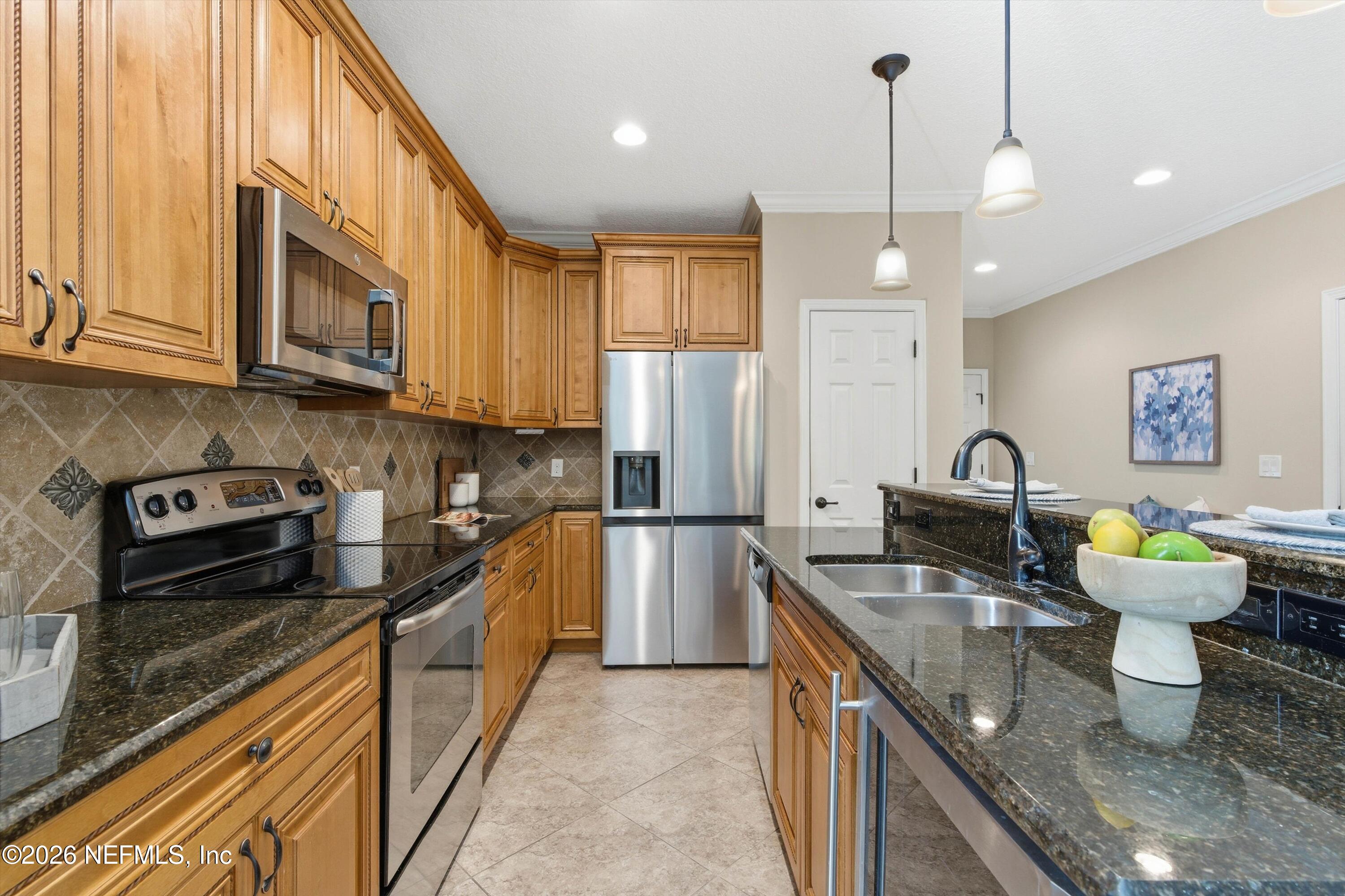 1733 Sanctuary Way Fleming Island, FL 32003 - Photo 6 of 39 a kitchen with stainless steel appliances granite countertop a sink a stove and a refrigerator