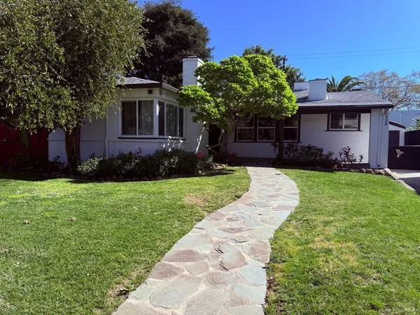 a front view of a house with a yard and potted plants
