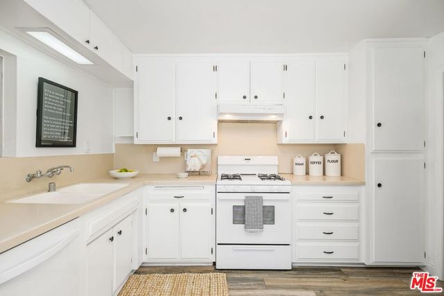 a kitchen with granite countertop white cabinets and white appliances