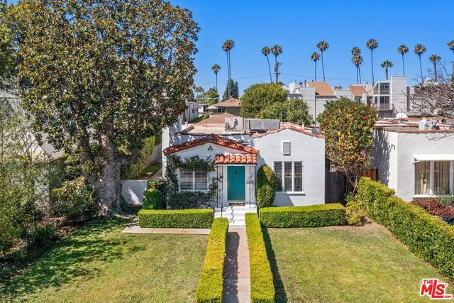 a view of a white house with a yard and plants