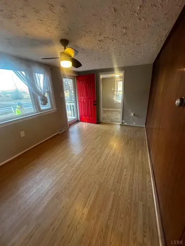 a view of empty room with wooden floor and fan