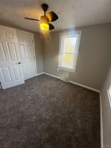 an empty room with a window and chandelier fan