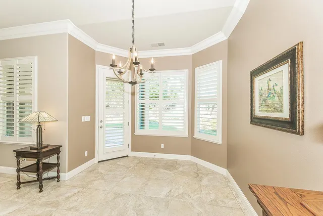 an empty room with a chandelier fan and windows