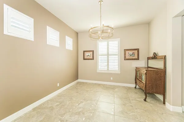 an empty room with a chandelier fan and windows