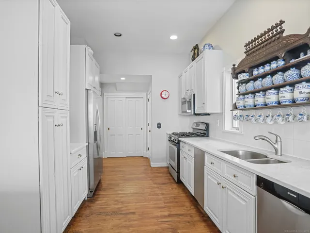 a view of a kitchen with a sink and dishwasher with wooden floor