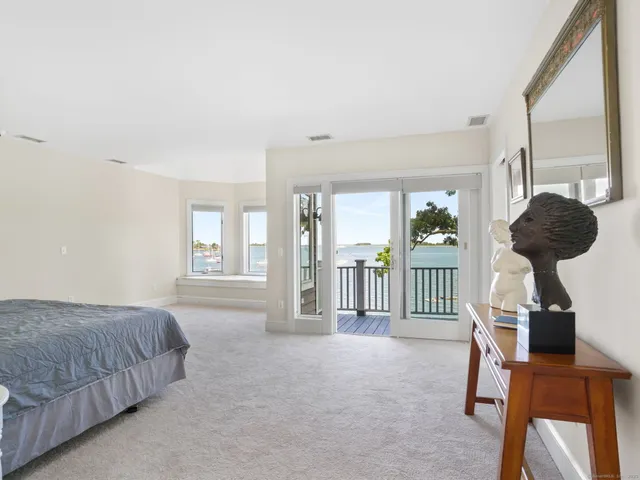 a spacious bedroom with a bed a table and large windows