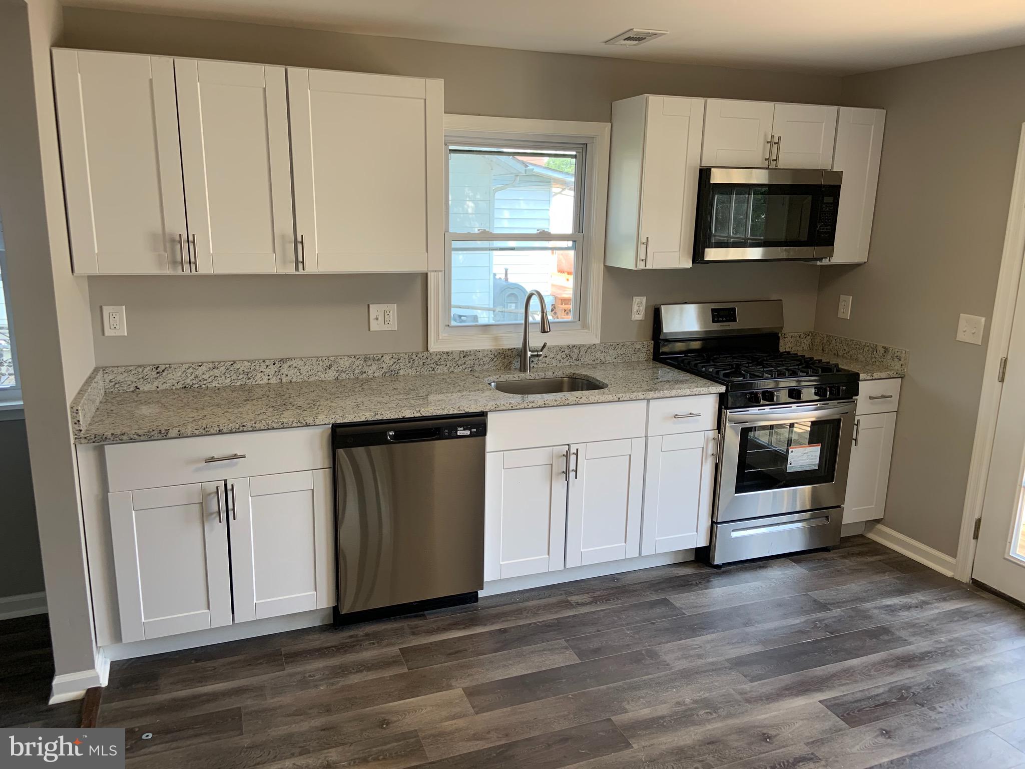 717 Fuselage Avenue Middle River, MD 21221 - Photo 8 of 31 a kitchen with stainless steel appliances granite countertop a stove a sink and a microwave