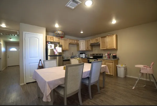 a kitchen with a dining table chairs and wooden floor