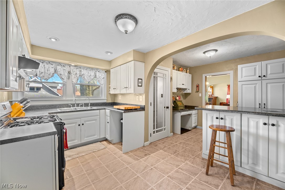 382 Baldwin Road Akron, OH 44312 - Photo 9 of 35 Kitchen with light tile floors, white cabinets, gas range, and sink