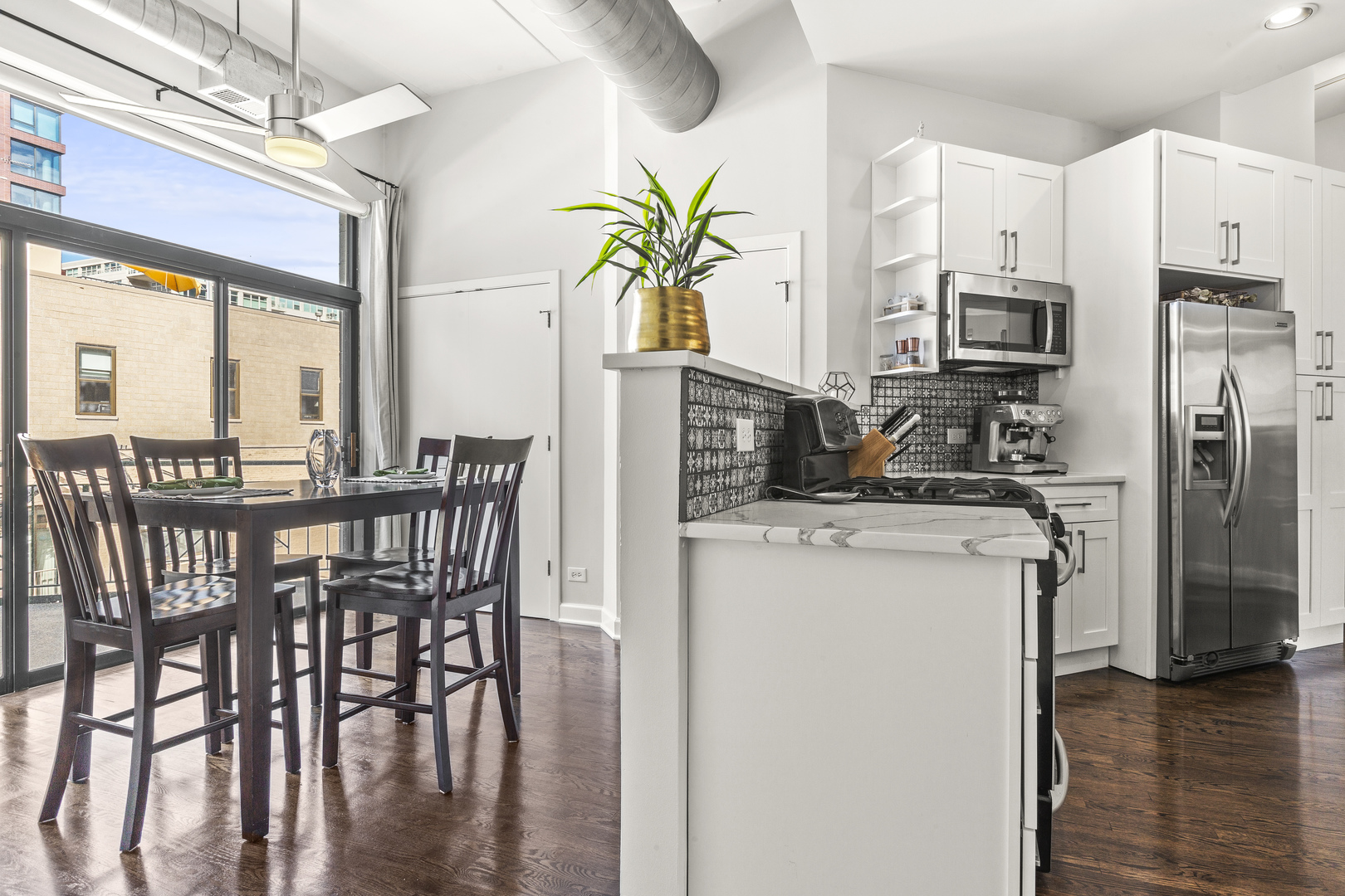 936 West Madison Street, Unit E4 Chicago, IL 60607 - Photo 10 of 21 a kitchen with stainless steel appliances granite countertop a stove a refrigerator a microwave a dining table and chairs with wooden floor