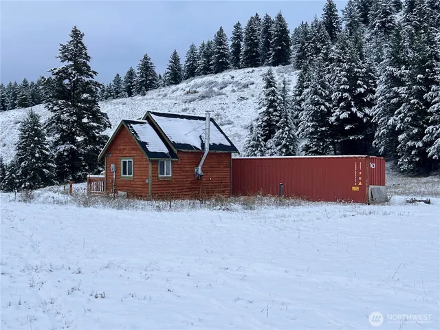a view of wooden house with a snow in the yard