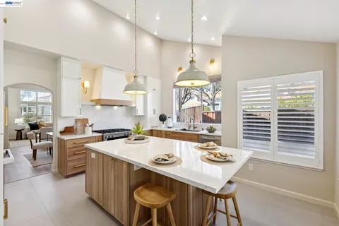 a kitchen with stainless steel appliances granite countertop a stove a refrigerator a oven a dining table and chairs with wooden floor