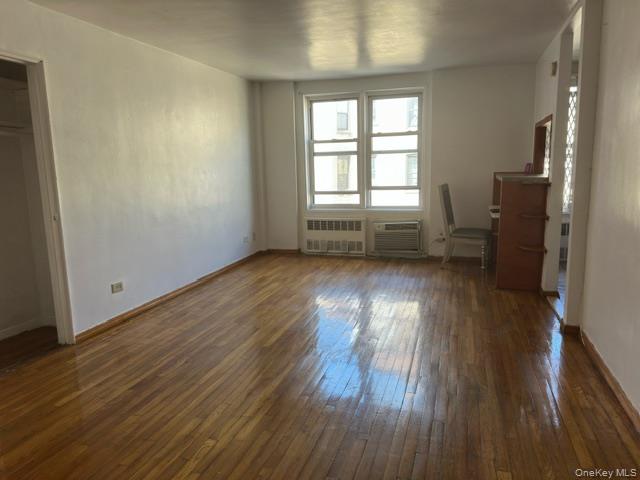 1332 Metropolitan Avenue, Unit 6A Bronx, NY 10462 - Photo 7 of 11 Unfurnished bedroom featuring dark wood-style floors, radiator heating unit, and an office area