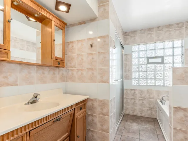 a bathroom with a sink a bathtub and next to a window