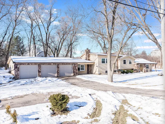 a front view of a house with a yard covered in snow