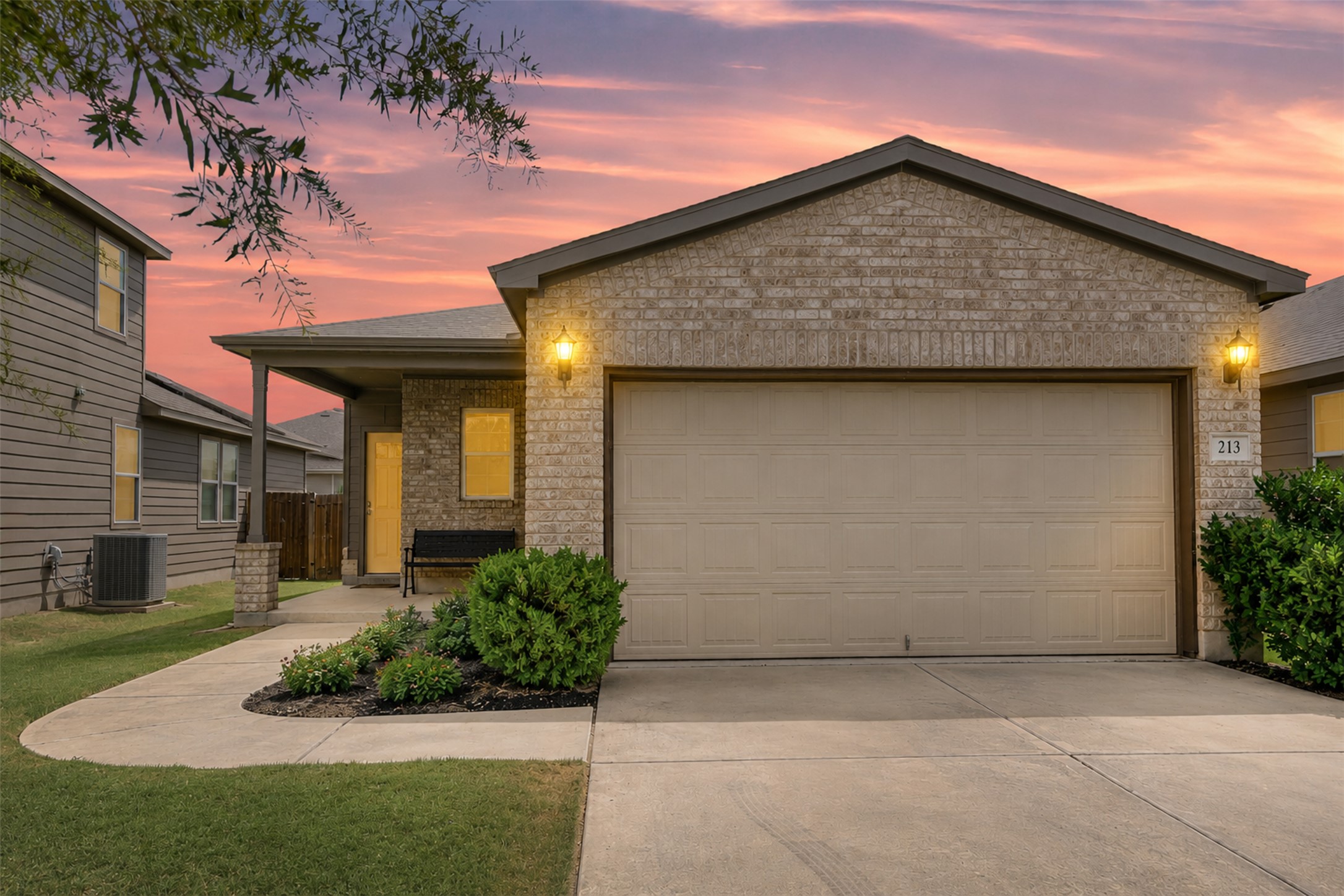 213 Ibis Falls Loop Jarrell, TX 76537 - Photo 1 of 37 A welcoming facade with a covered entry, mature landscaping, and an attached garage.