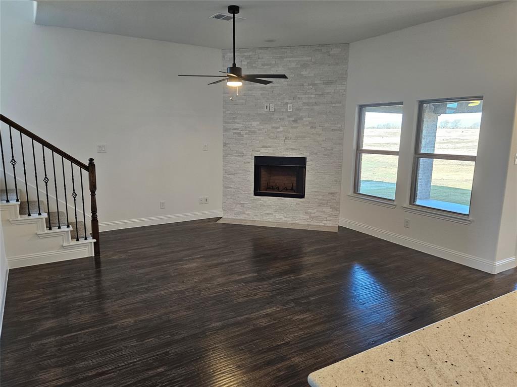 1507 Enloe Road Howe, TX 75459 - Photo 7 of 27 an empty room with wooden floor fireplace and windows