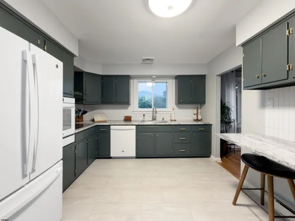 a large kitchen with a stove a refrigerator a sink dishwasher with a dining table and chair