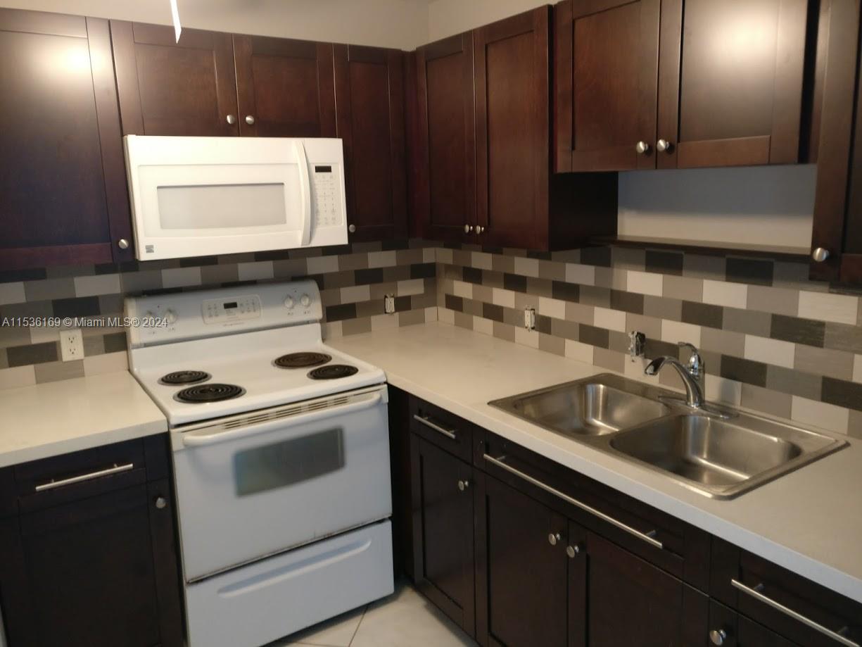 a kitchen with sink a microwave and cabinets