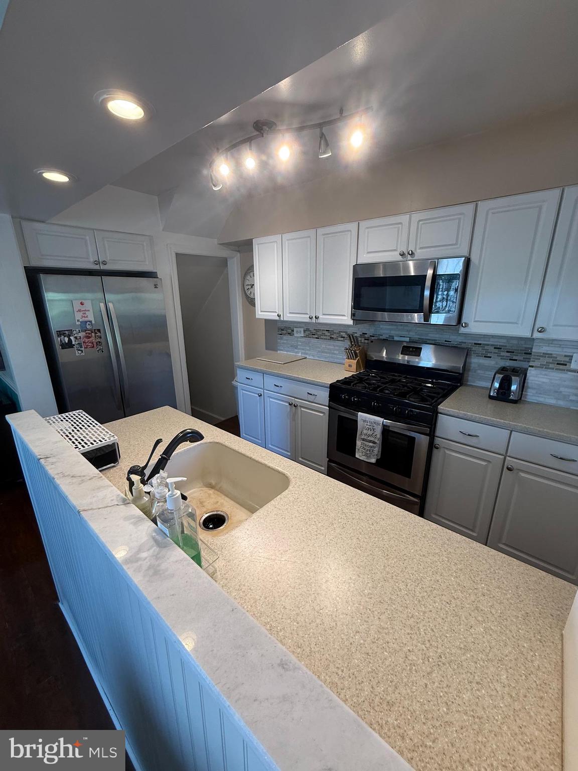 2235 Hawthorne Road Baltimore, MD 21220 - Photo 11 of 35 a kitchen with stainless steel appliances granite countertop a sink a stove a refrigerator a microwave oven with white cabinets and wooden floor