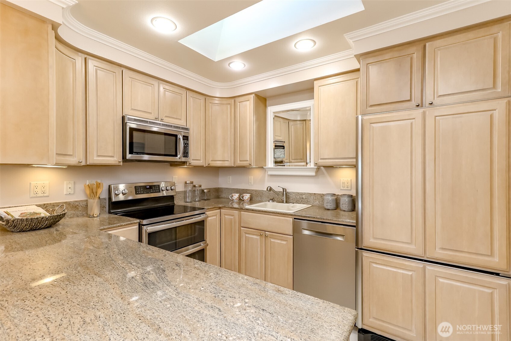 4444 44th Avenue Southwest, Unit 405 Seattle, WA 98116 - Photo 7 of 32 a kitchen with stainless steel appliances granite countertop a refrigerator a stove top oven a sink and dishwasher with wooden floor