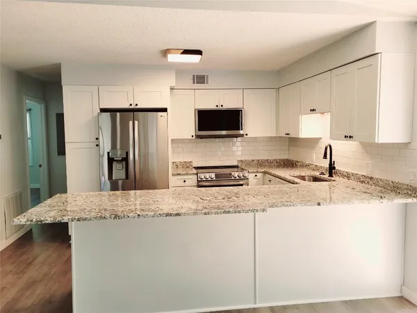 a kitchen with stainless steel appliances granite countertop a refrigerator a stove a sink and a granite counter tops