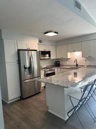 a kitchen with stainless steel appliances granite countertop a refrigerator a stove a sink and a microwave