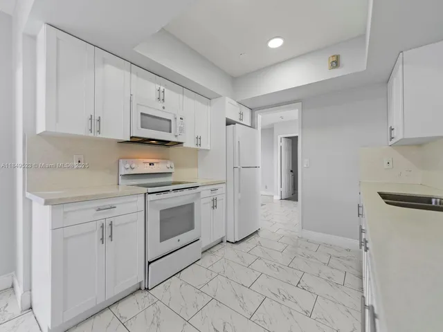 a kitchen with white cabinets and white appliances