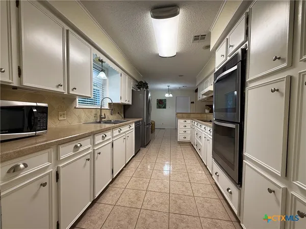 a large kitchen with stainless steel appliances granite countertop a stove and a refrigerator