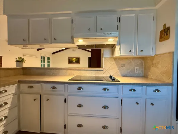 a kitchen with granite countertop white cabinets and white appliances