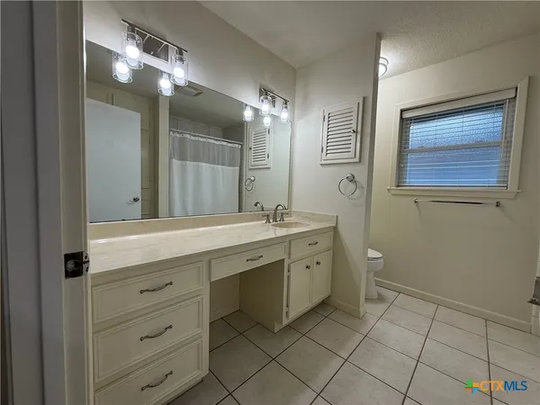 a spacious bathroom with a granite countertop sink a toilet and a mirror