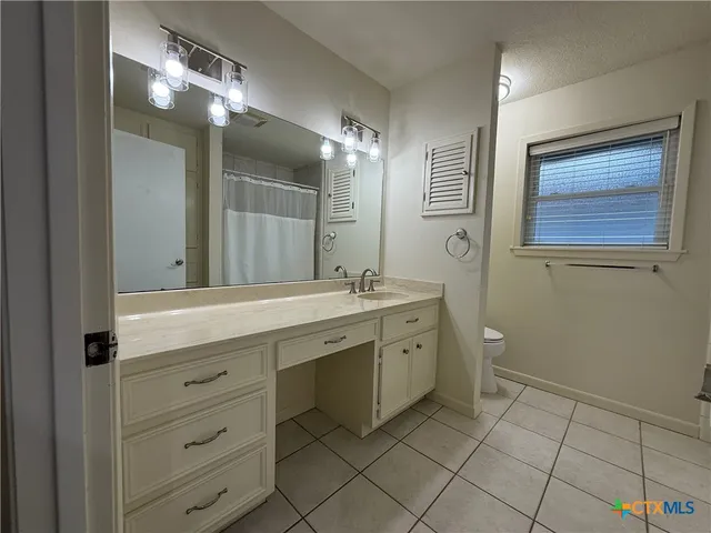 a spacious bathroom with a granite countertop sink a toilet and a mirror