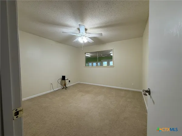 an empty room with windows and ceiling fan