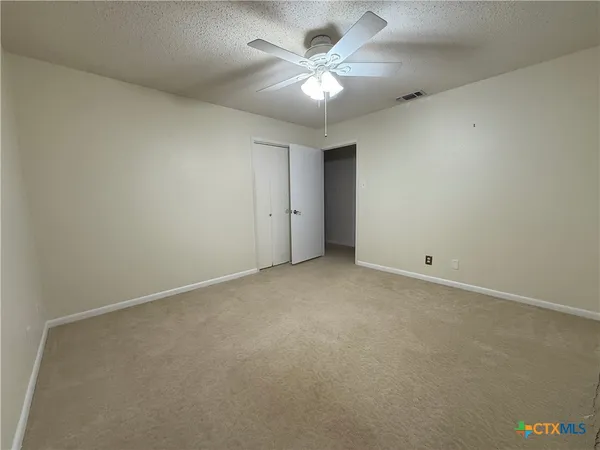 an empty room with a chandelier fan and windows