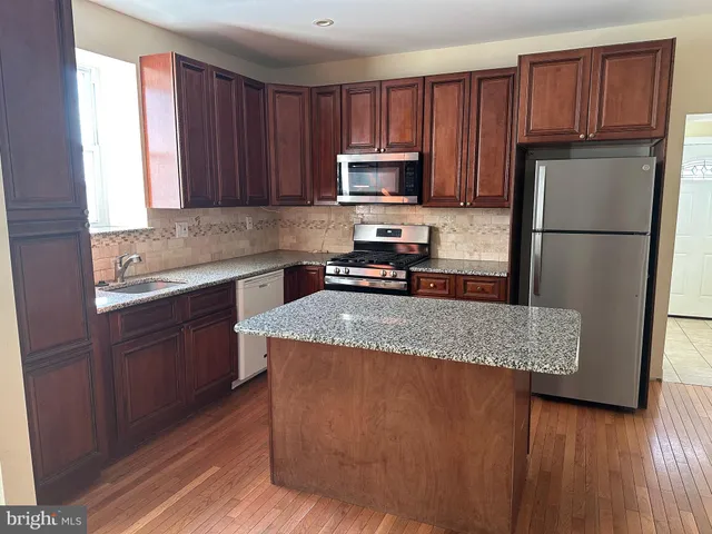 a kitchen with kitchen island granite countertop wooden cabinets a refrigerator and a sink