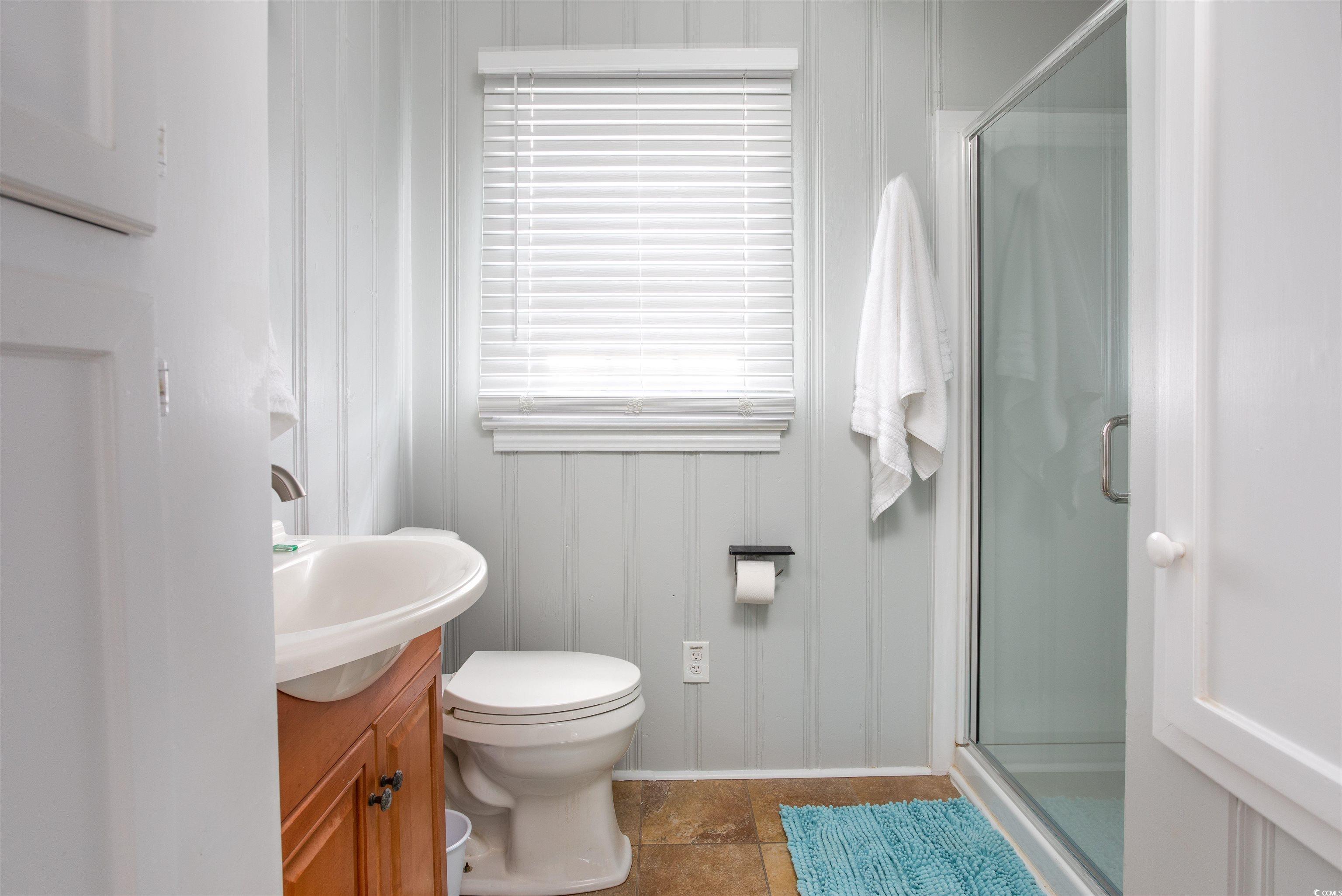 214 Yucca Avenue Murrells Inlet, SC 29576 - Photo 20 of 22 Bathroom featuring vanity, a stall shower, dark tile patterned floors, and a decorative wall