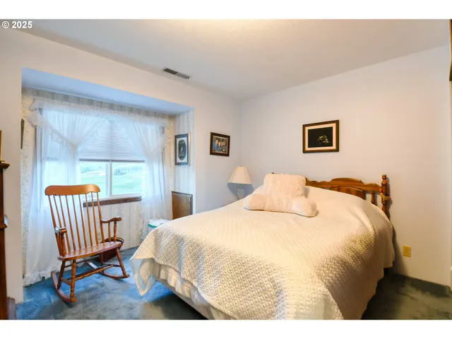 a bedroom with a bed a painting and a window