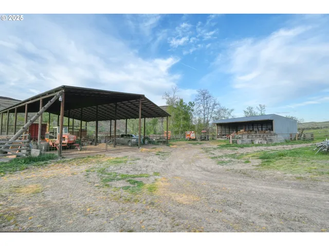 a backyard of a house with table and chairs under an umbrella