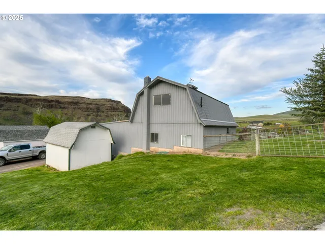 a view of a house with a big yard potted plants and a large window