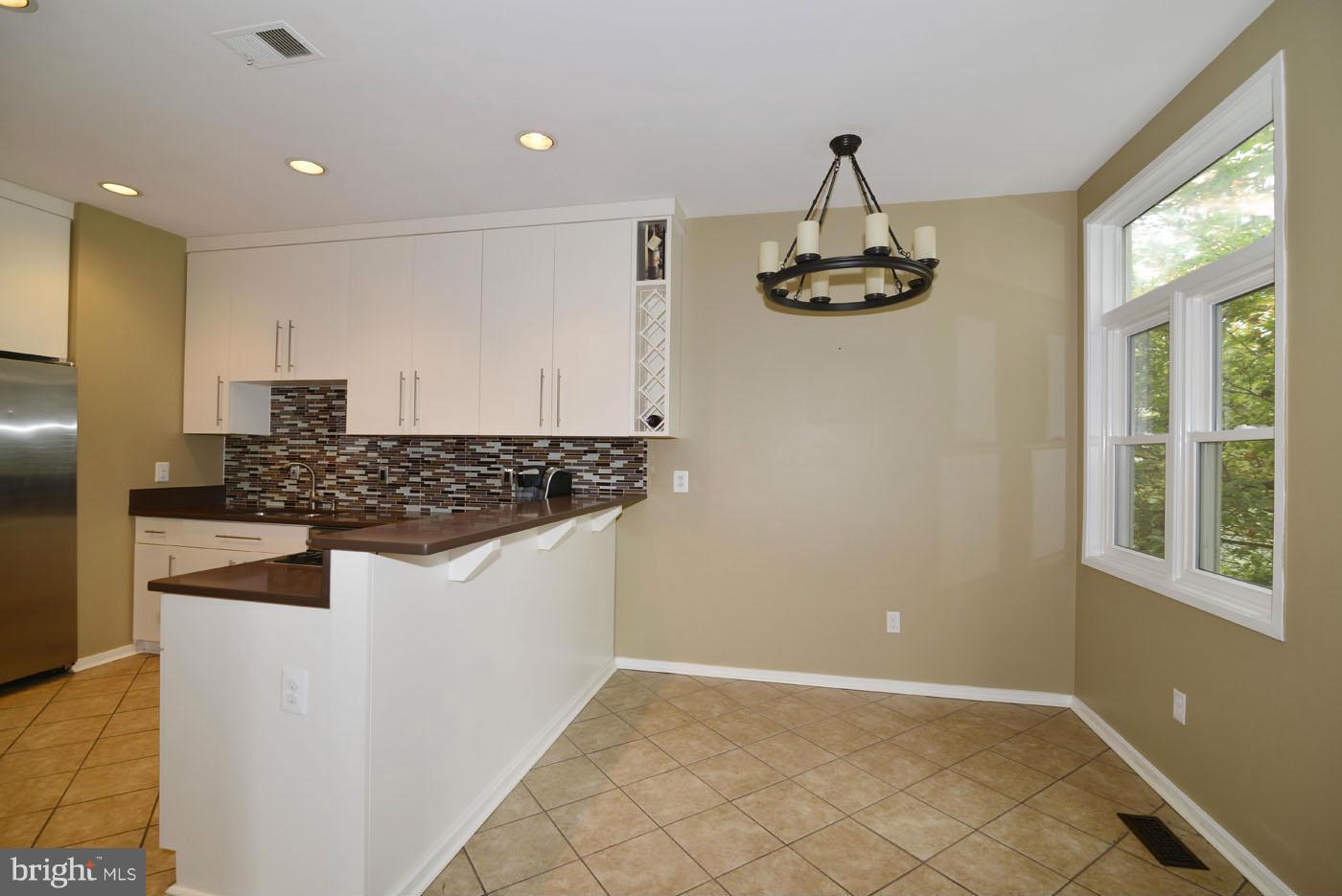 2040 Beacon Place Reston, VA 20191 - Photo 5 of 30 a kitchen with kitchen island white cabinets and window