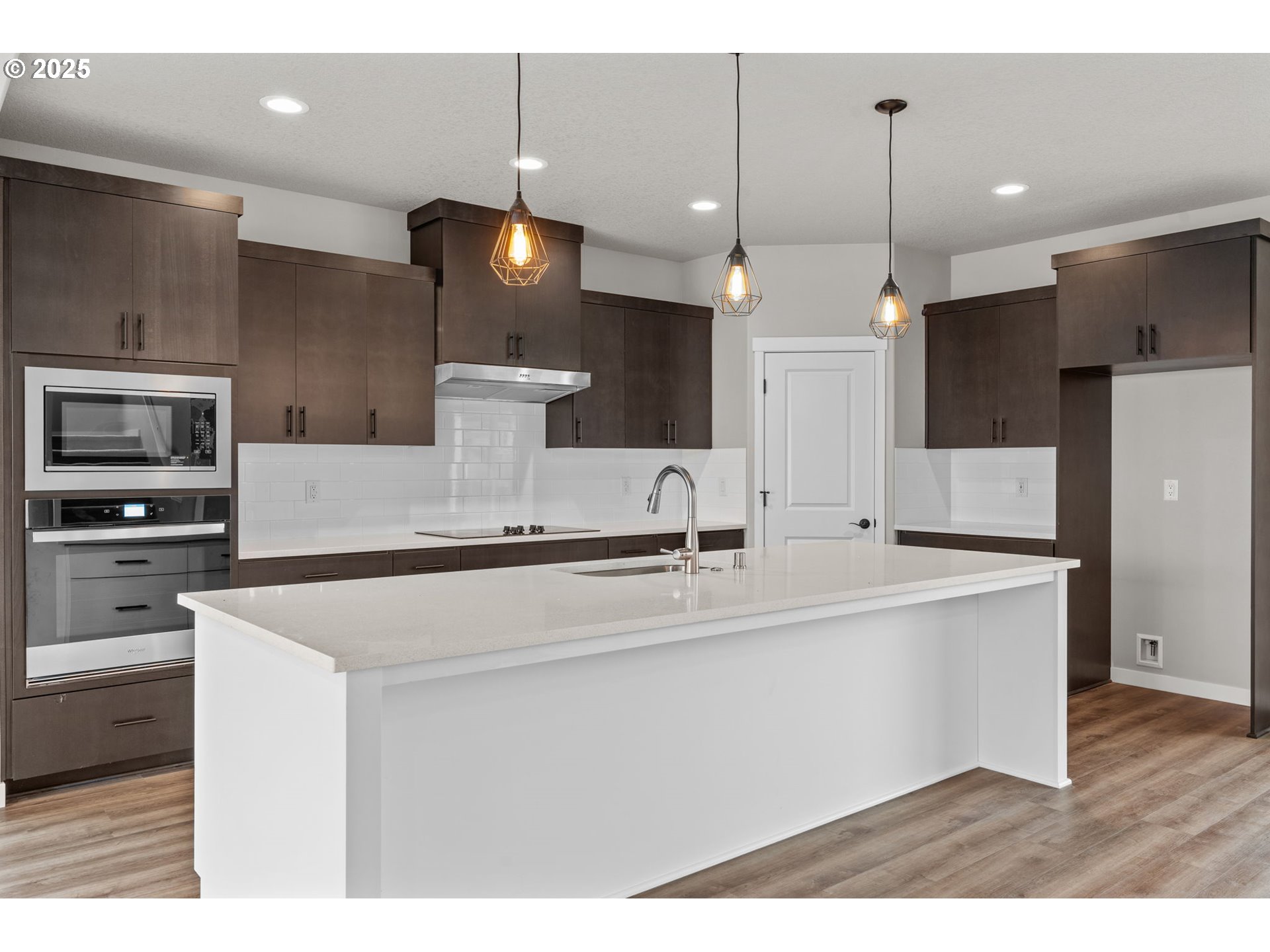 1105 Northwest 111th Circle Vancouver, WA 98685 - Photo 12 of 48 a large white kitchen with a large island oven a stove a refrigerator white cabinets and couches with wooden floor