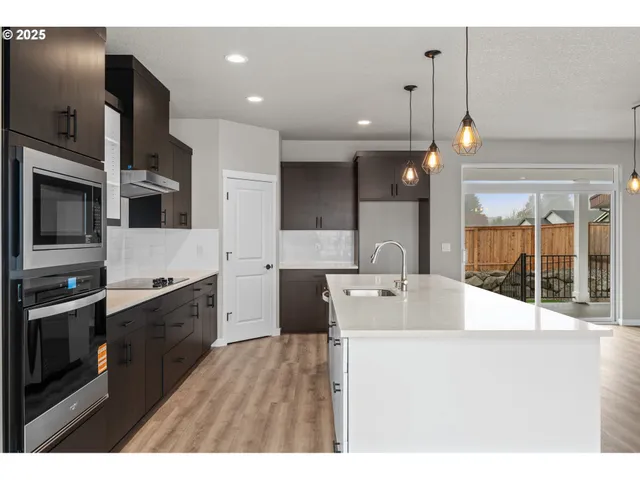 a large kitchen with a large counter top a sink stainless steel appliances and cabinets
