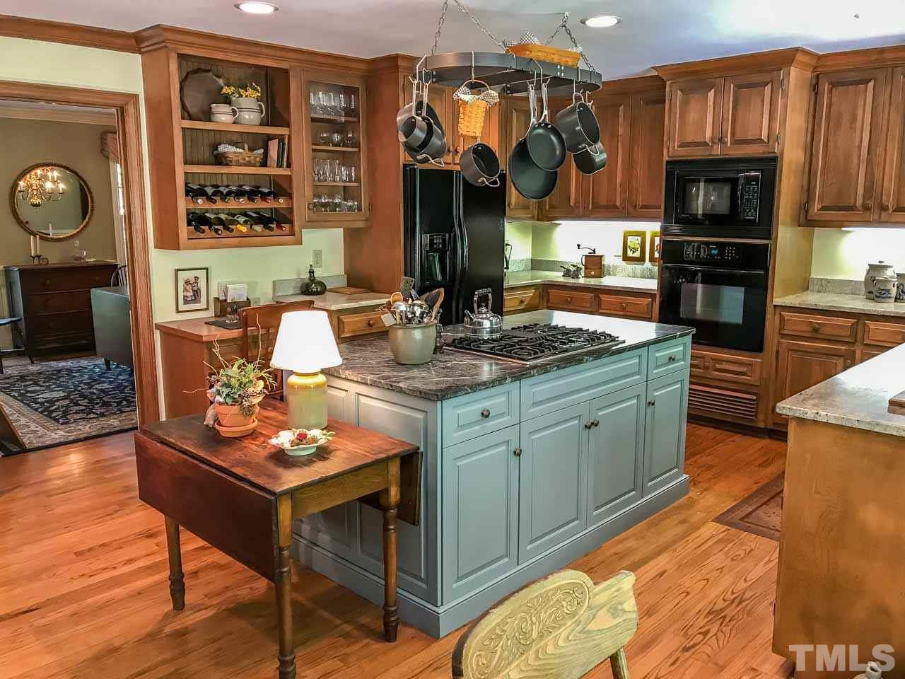 1806 Grande Oaks Road Durham, NC 27712 - Photo 15 of 25 a kitchen with a stove a sink dishwasher and a dining table with wooden floor
