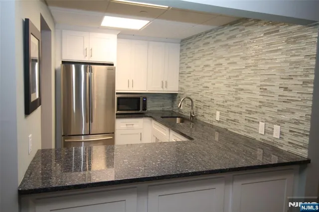 a kitchen with stainless steel appliances granite countertop a refrigerator a sink and a stove