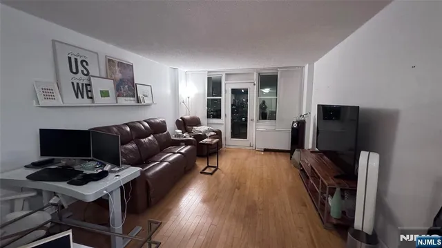 a living room with furniture a flat screen tv and a refrigerator