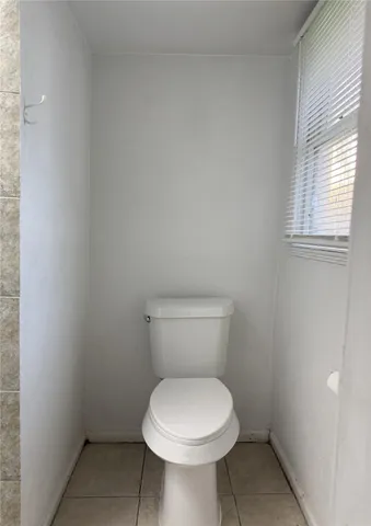 a white toilet sitting in a bathroom next to a window